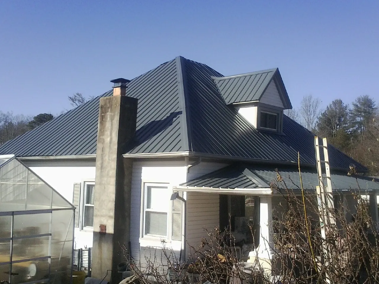 Dark blue standing seam metal roof on a white farmhouse with dormer — Slate & Tile Roof Repair by Roofing Brothers in Papillion