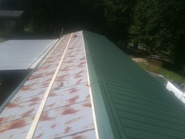 Old rusted panels beside newly installed green metal roofing — Wind Damage Roof Repair by Roofing Brothers in Papillion