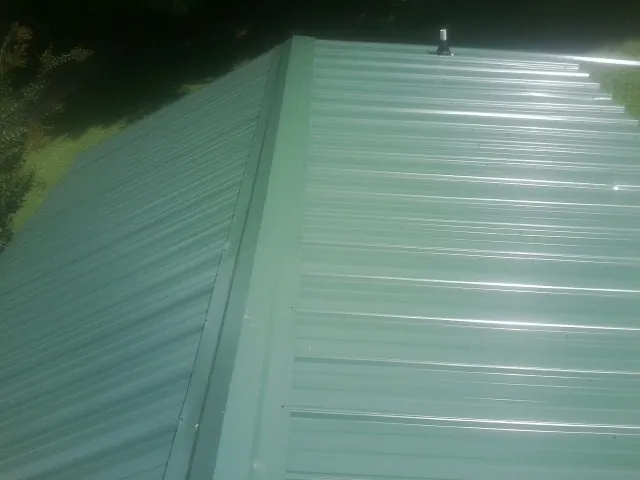 New green metal panels meeting at the ridge of a roof — Flat Roof Repair work by our crew in Papillion