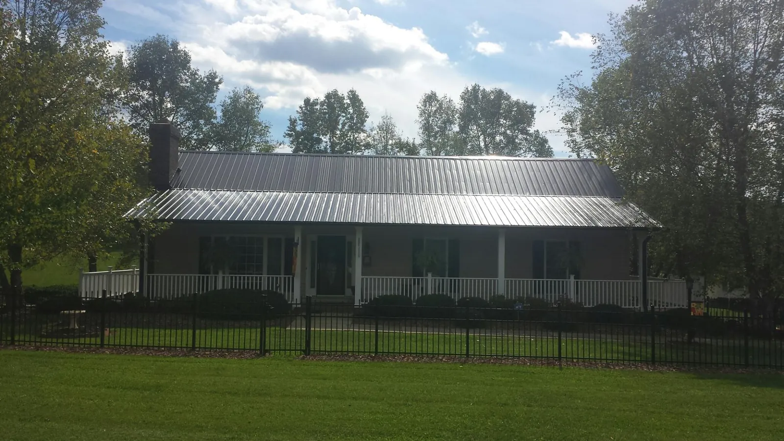 Gray metal roof on a brick ranch with a full width front porch — Gutter Guard Installation work by our crew in Papillion