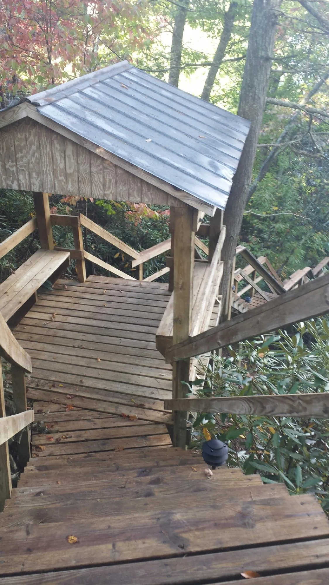 Metal roofed shelter over wooden steps on a wooded walkway — Skylight Repair & Installation work by our crew in Papillion