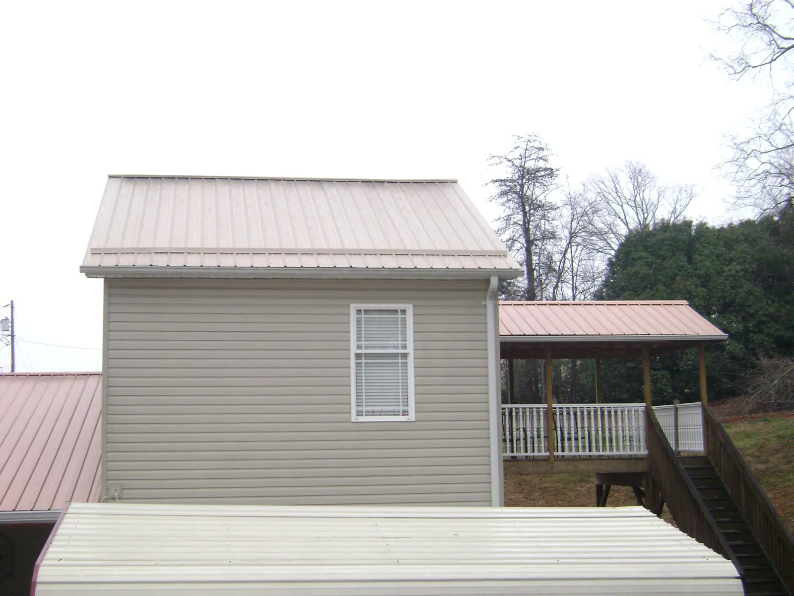 Tan metal roofs on a two story addition and attached porch, from a Roof Replacement job in Papillion