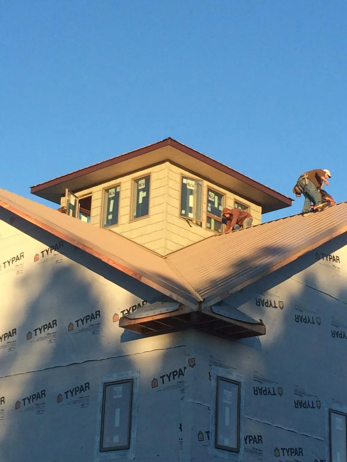 Roofers working around a rooftop cupola on a new metal roof at sunset — Roof Waterproofing in Papillion by Roofing Brothers